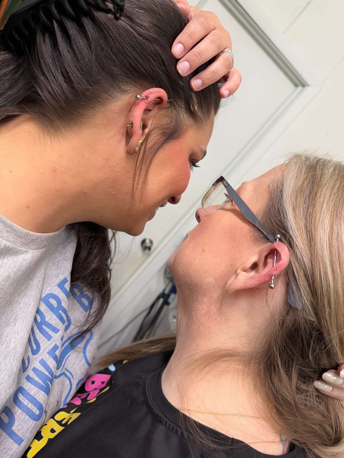 Two friends showing off their matching fresh industrial piercings at Off Grid Tattoo