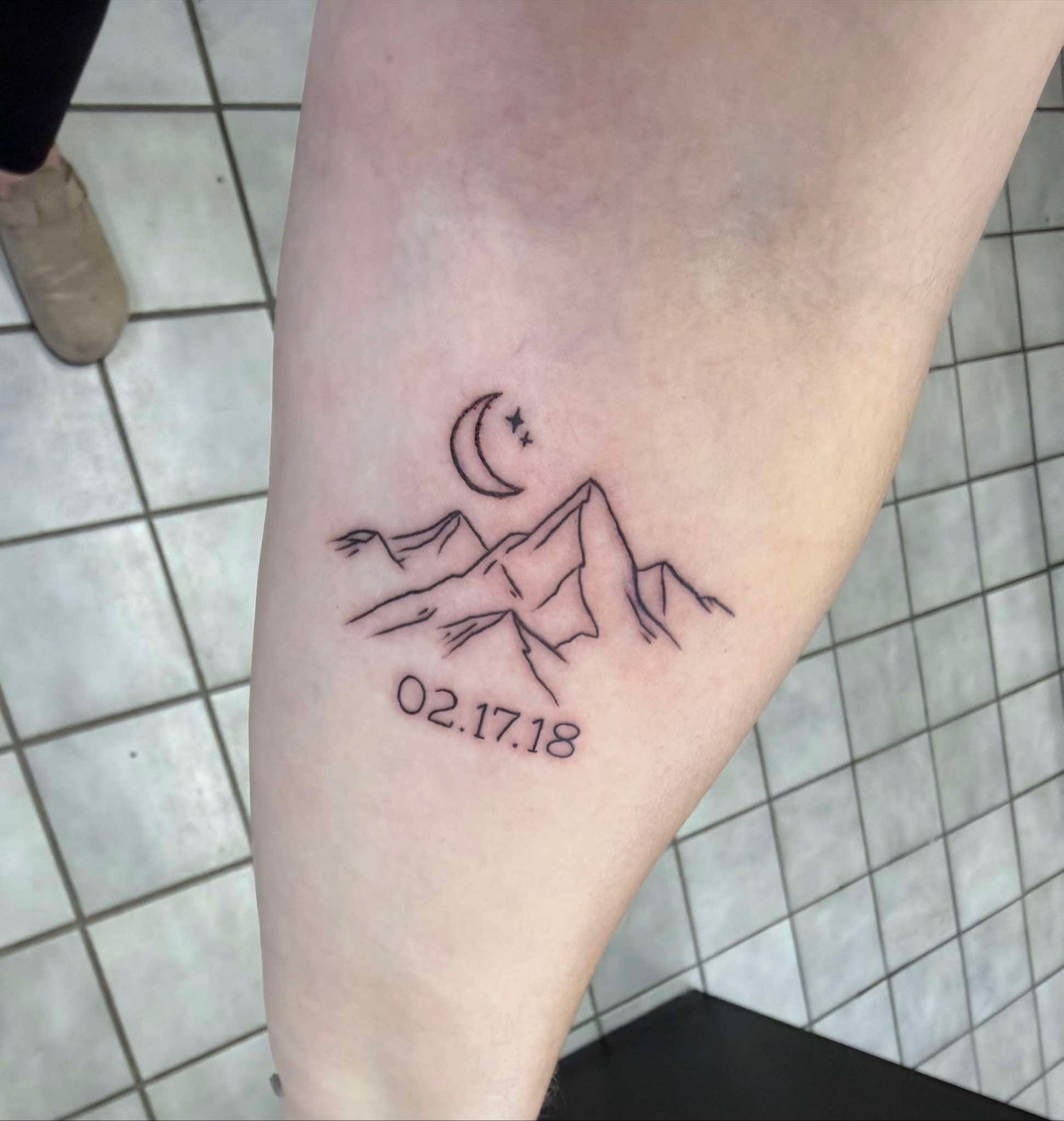 Fine line mountain range tattoo with crescent moon and date 02.17.18 on a calf, Off Grid Tattoo Ellijay
